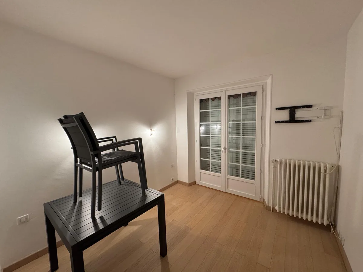 Salon rénové avec murs clairs, parquet et éclairage mural