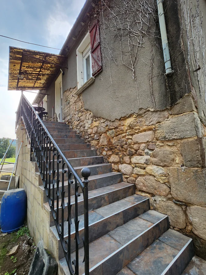 Escalier extérieur carrelé le long d'un mur ancien en pierre