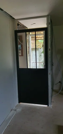 Pose d'une verrière intérieure noire dans une maison rénovée
